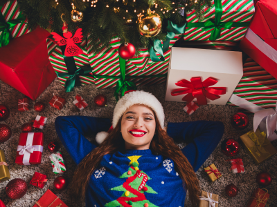 Woman surrounded by Christmas gifts and tree